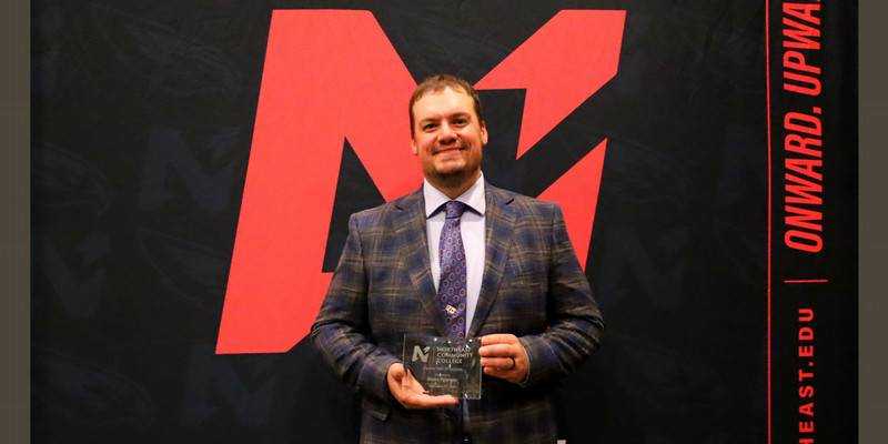 Shane Peterson holding an Achievement Award.