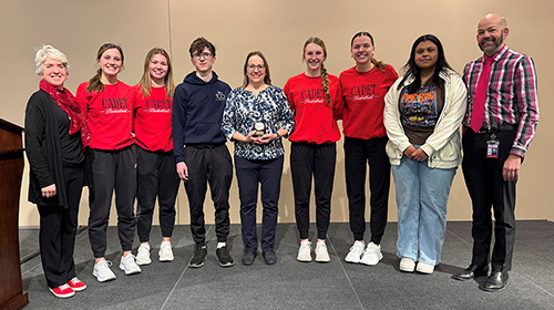 math instructor receiving award surrounded by students