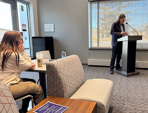 professor reads at podium to audience