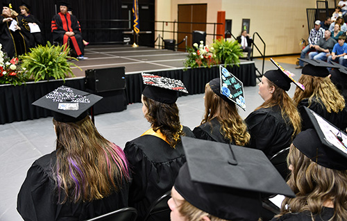 view of stage from graduate's perspective at commencement, decorated grad caps
