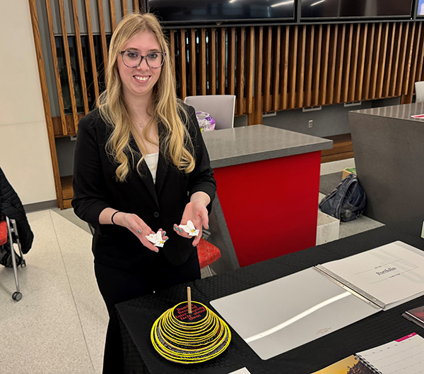 graphic design student shows hive and a pair of bees she made