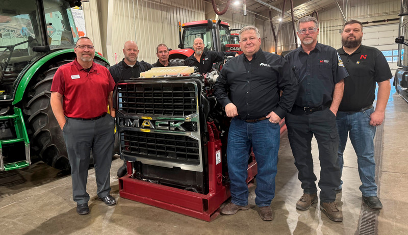 RDO representatives and Northeast faculty standing next to truck engine. 