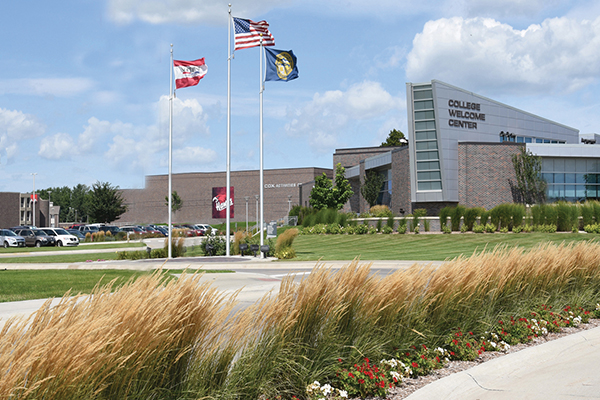 College welcome center with flags and landscaped entrance.