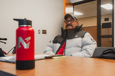Student seated at a classroom table with a water bottle and notebook