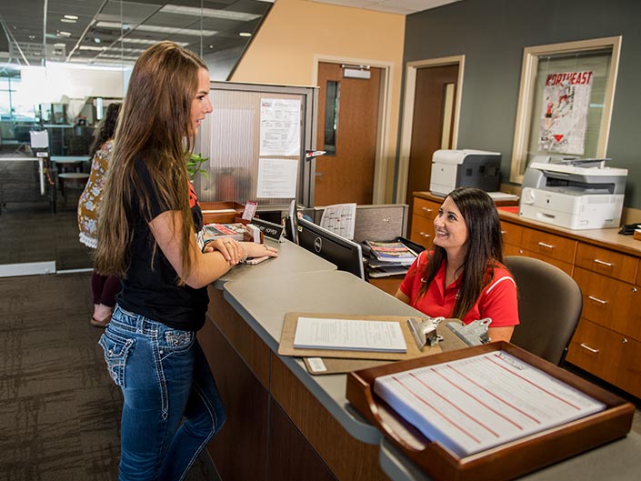 student talking to employee at admissions desk