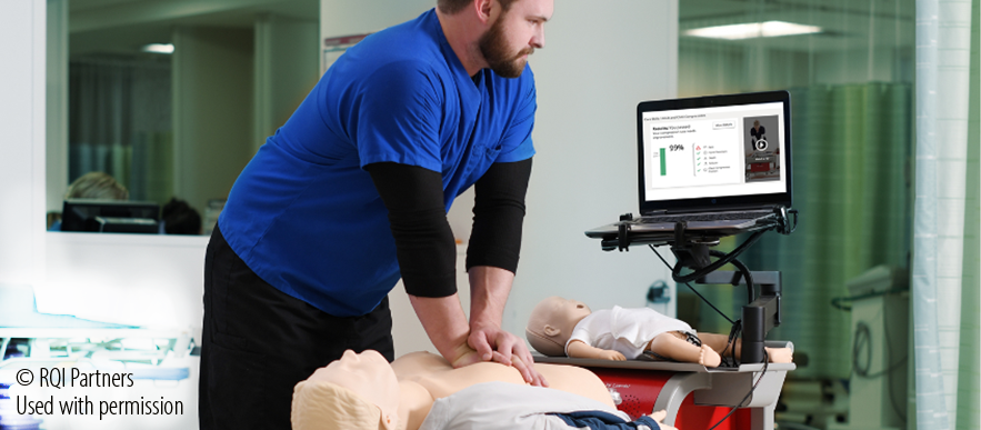 man looking at monitor and practicing CPR on a dummy