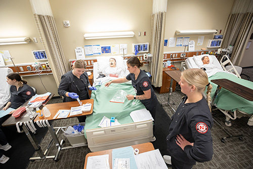 nursing students working with a manikin and medical equipment