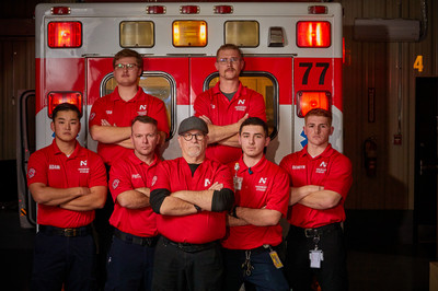 Paramedic students and instructors pose in front of an ambulance during hands-on emergency medical training.