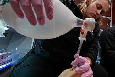 Student providing care to mannikin patient in ambulance. 