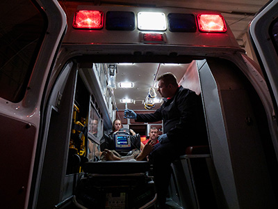 view into back ambulance with lights on, paramedics with a patient